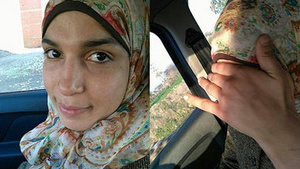 An Arabian woman in a hijab enjoying herself in a car.