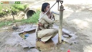 A young village girl is taking a bath in a sari and is captured by the camera.